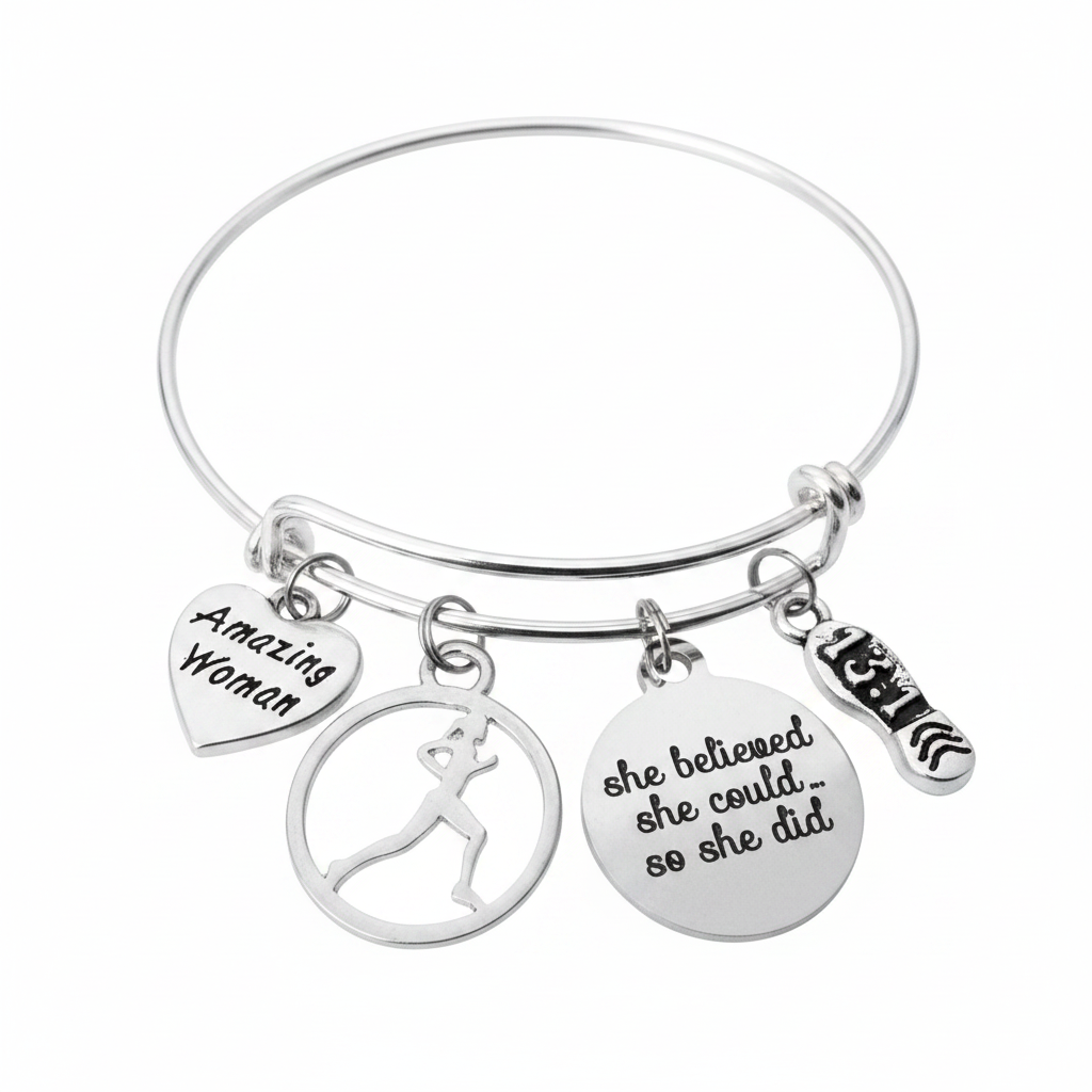 Silver-plated expandable wire bangle bracelet with four charms: heart charm engraved Amazing Woman, circular cutout female runner silhouette charm, round disc charm engraved she believed she could so she did, and 13.1 running shoe charm — motivational marathon gift for women runners