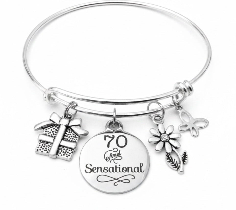Silver expandable bangle bracelet with '70 and Sensational' engraved pendant, gift box charm, daisy flower charm, and butterfly charm by Jules Obsession