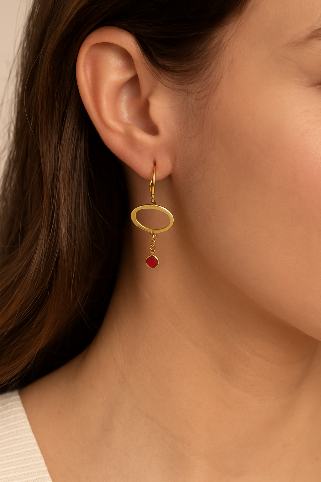 Gold earring with a red gemstone