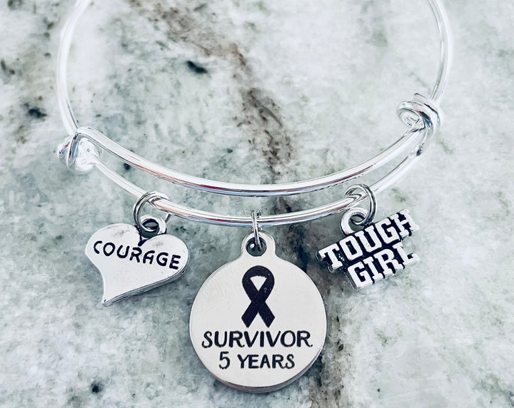 Silver expandable bangle bracelet with Tough Girl, Survivor 5 Years ribbon, and Courage heart charms — cancer survivor milestone gift
