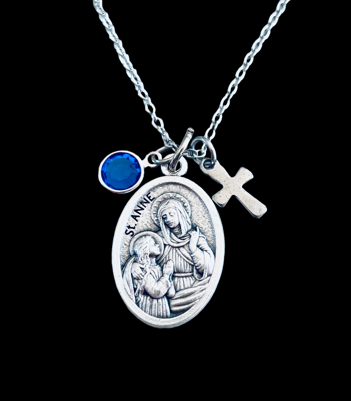 A silver oxidized Saint Anne medal necklace with a cross charm and a birthstone, displayed on a stainless steel chain 