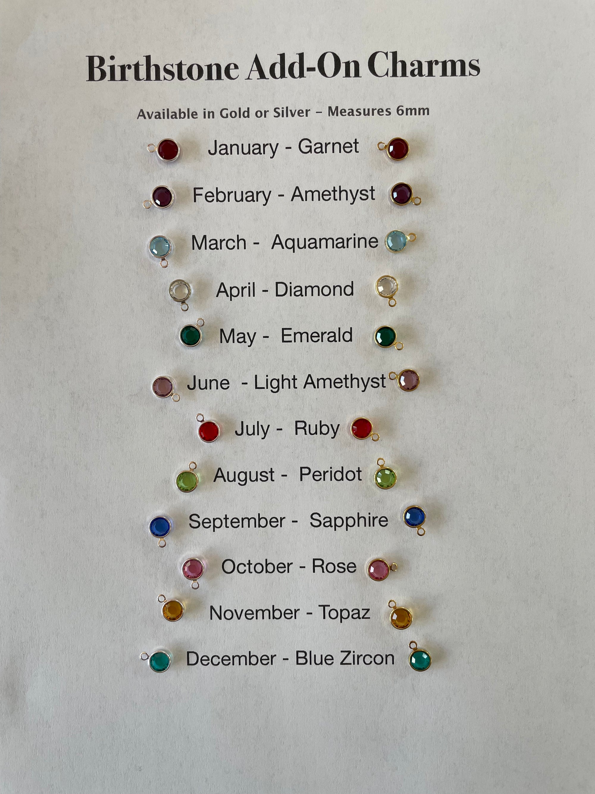 Set of birthstone add-on charms on a gray background with corresponding months and gemstones listed.