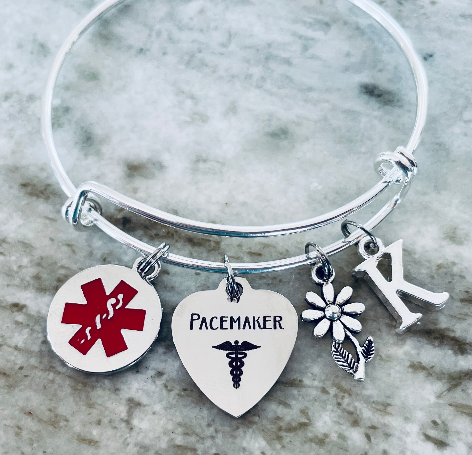 medical alert bracelet “Pacemaker,” daisy flower, and initial charm.