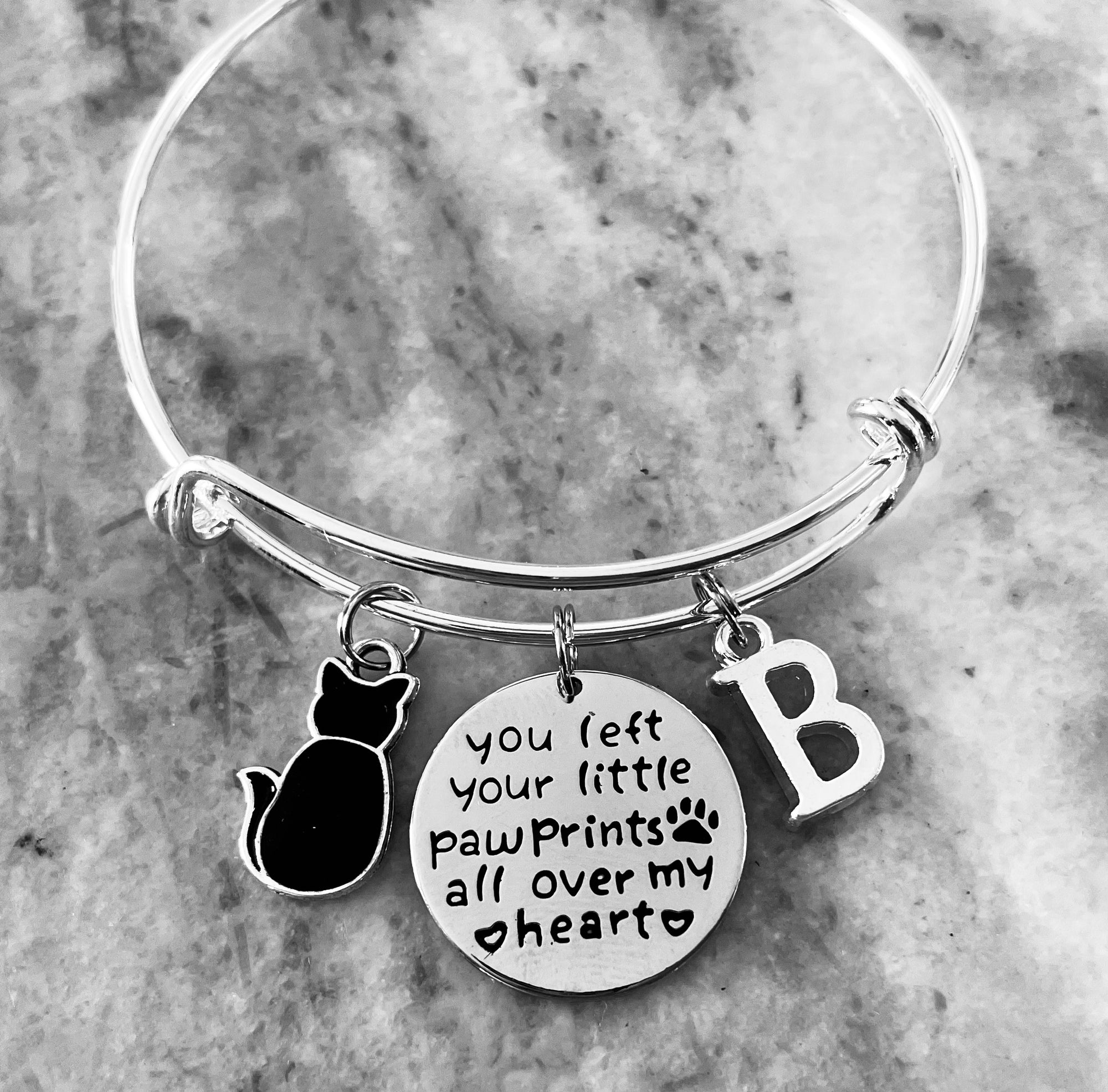 Silver expandable cat memorial bracelet with black cat charm, engraved pawprint message, and personalized initial