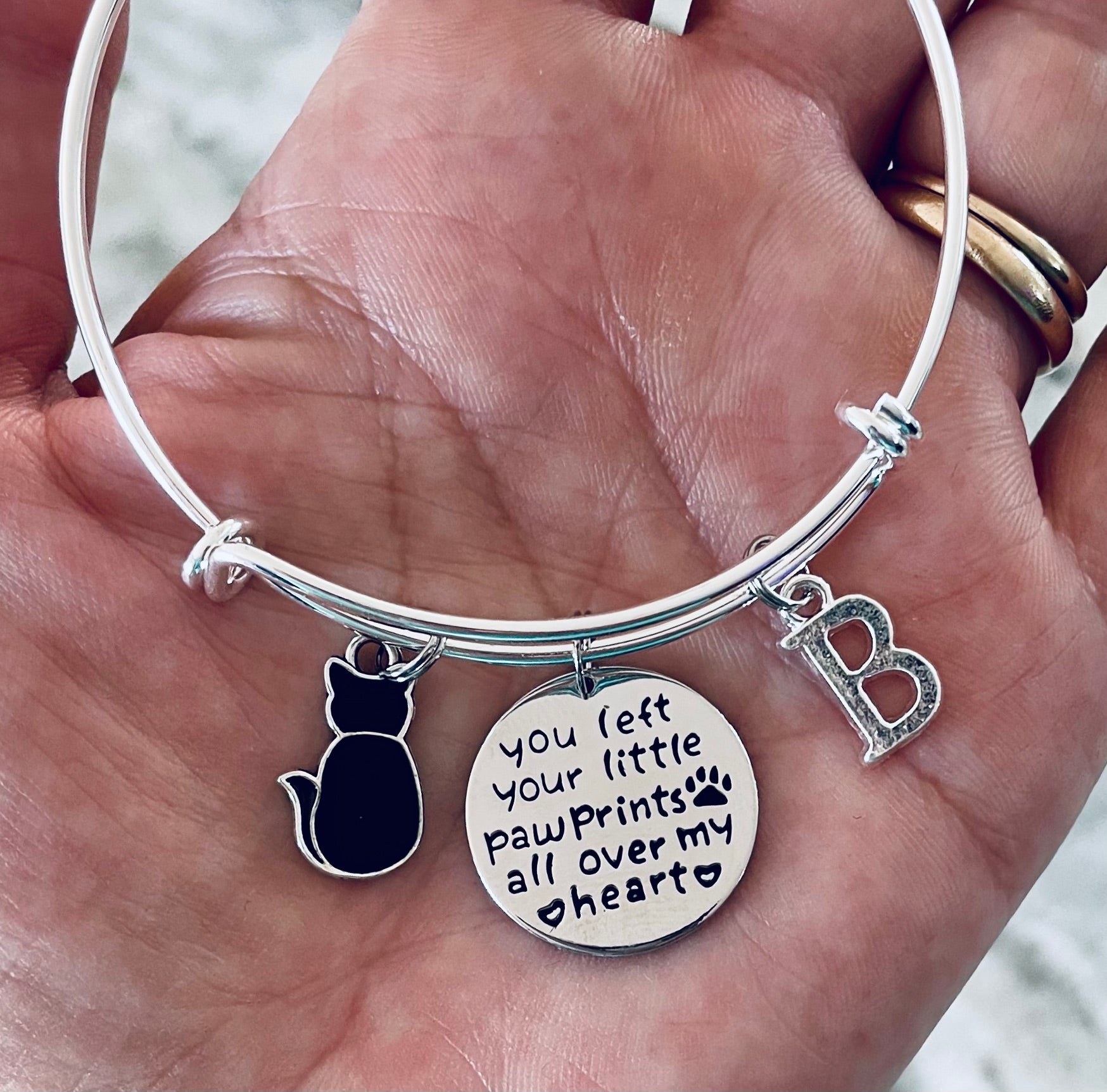 Silver bracelet with cat charm, paw prints charm, and letter