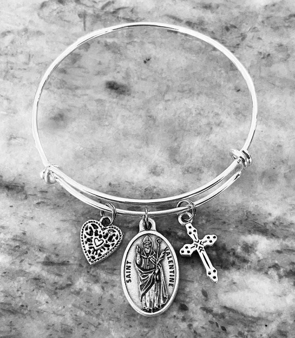 Expandable silver Saint Valentine charm bracelet with heart and cross on silver-tone bangle