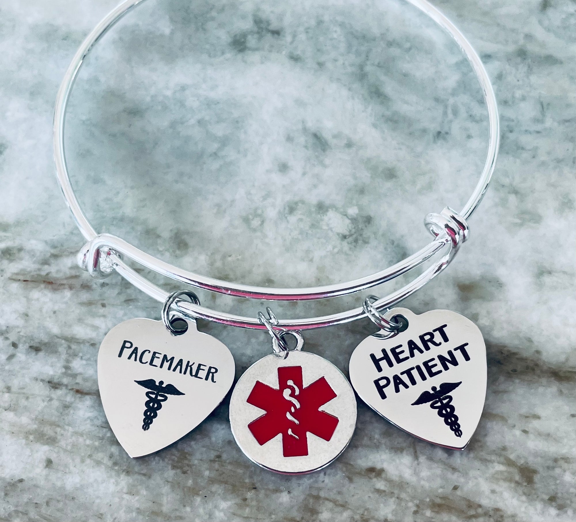 Medical ID bracelet for heart patients with engraved charms and red emergency alert symbol