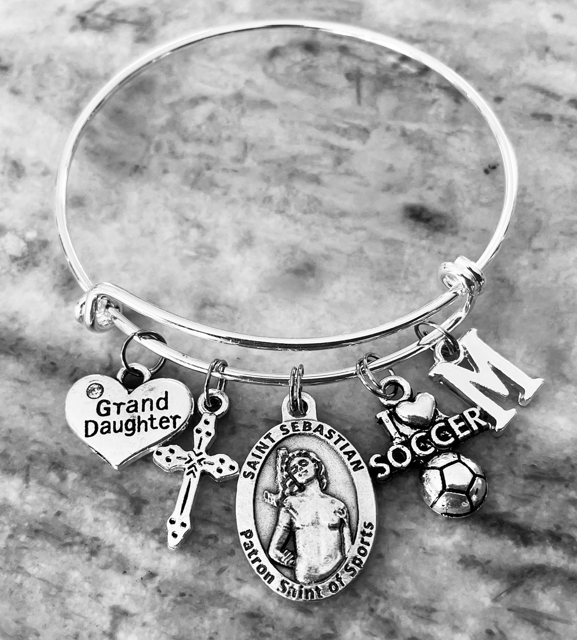 Granddaughter charm bracelet with Saint Sebastian medal, soccer charm, cross, initial, and heart Grand Daughter charm on silver expandable bangle
