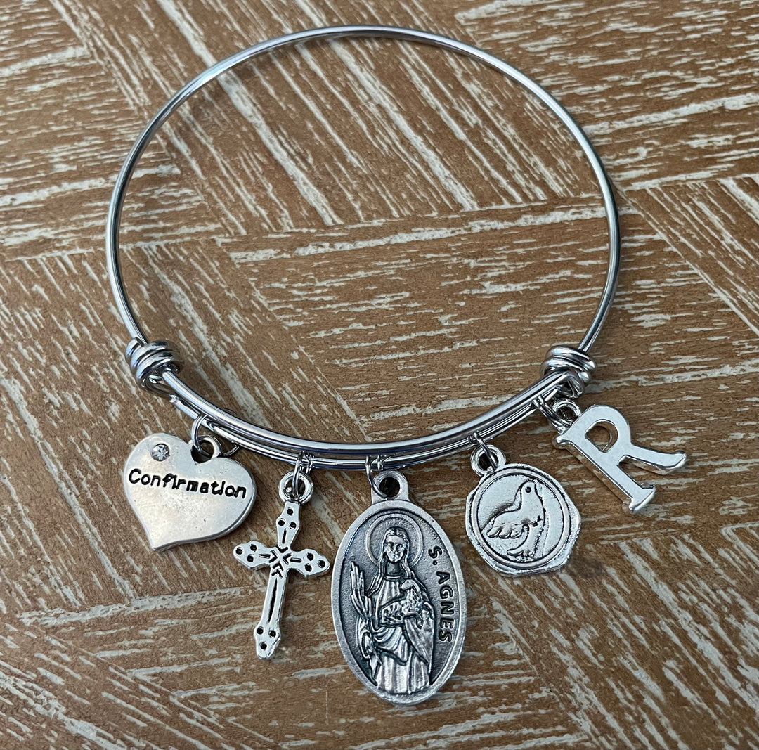Confirmation charm bangle bracelet with Saint Agnes oval saint medal, cross charm, dove medallion, Confirmation heart, and letter initial charm 