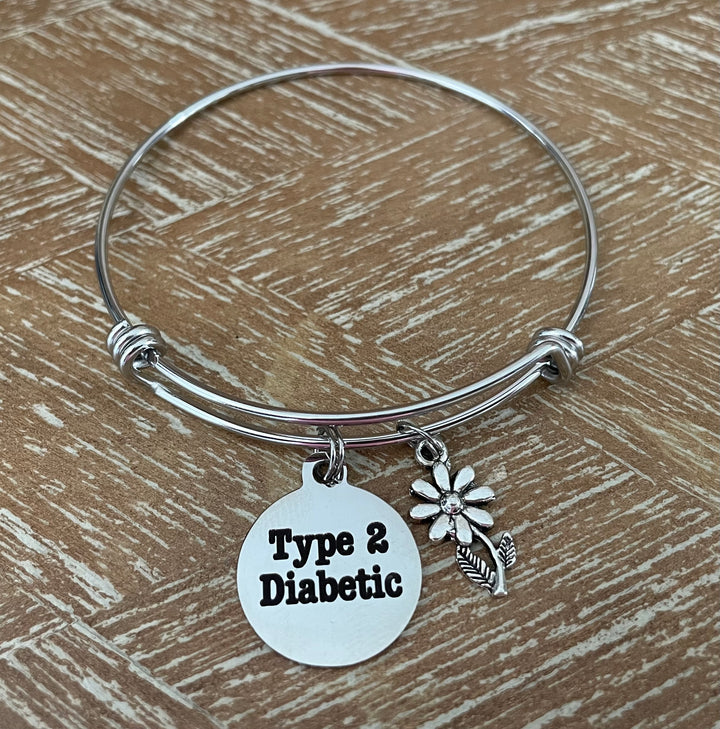 A silver wire bangle bracelet with a round disc charm engraved &