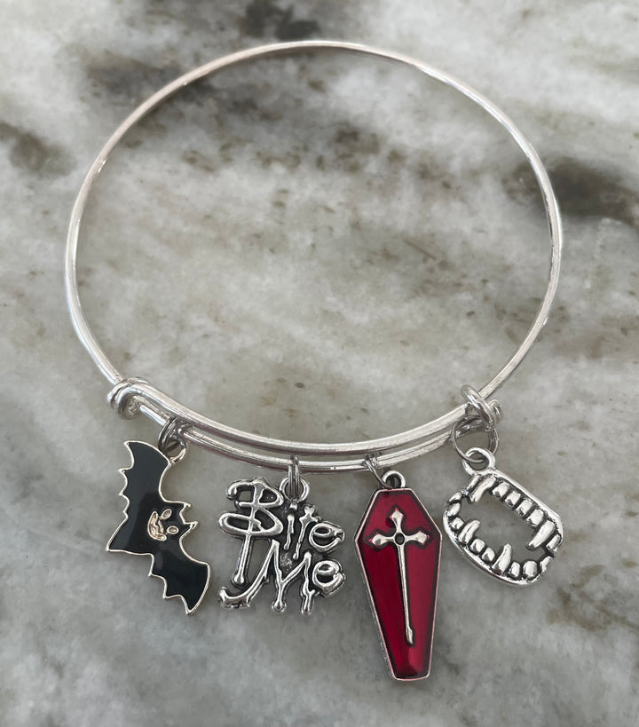 A silver-tone bangle bracelet with four Halloween-themed charms: a black bat, &