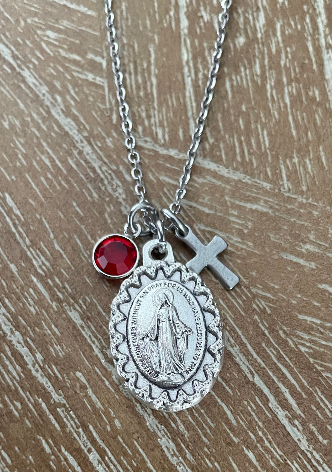 oxidized silver Virgin Mary miraculous medal with scalloped decorative border, bas-relief image of Mary with outstretched arms, and prayer text engraved around the border