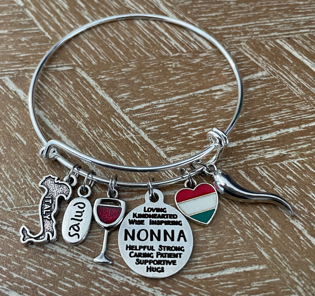 A silver-tone expandable bangle bracelet with multiple charms, including a heart-shaped Italian flag charm, a wine glass charm, and a round charm that reads &