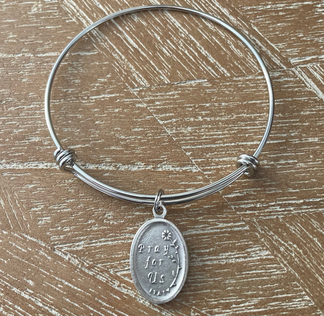 Silver expandable bangle bracelet with an oval Saint Pio relic medal attached with a stainless steel split ring
