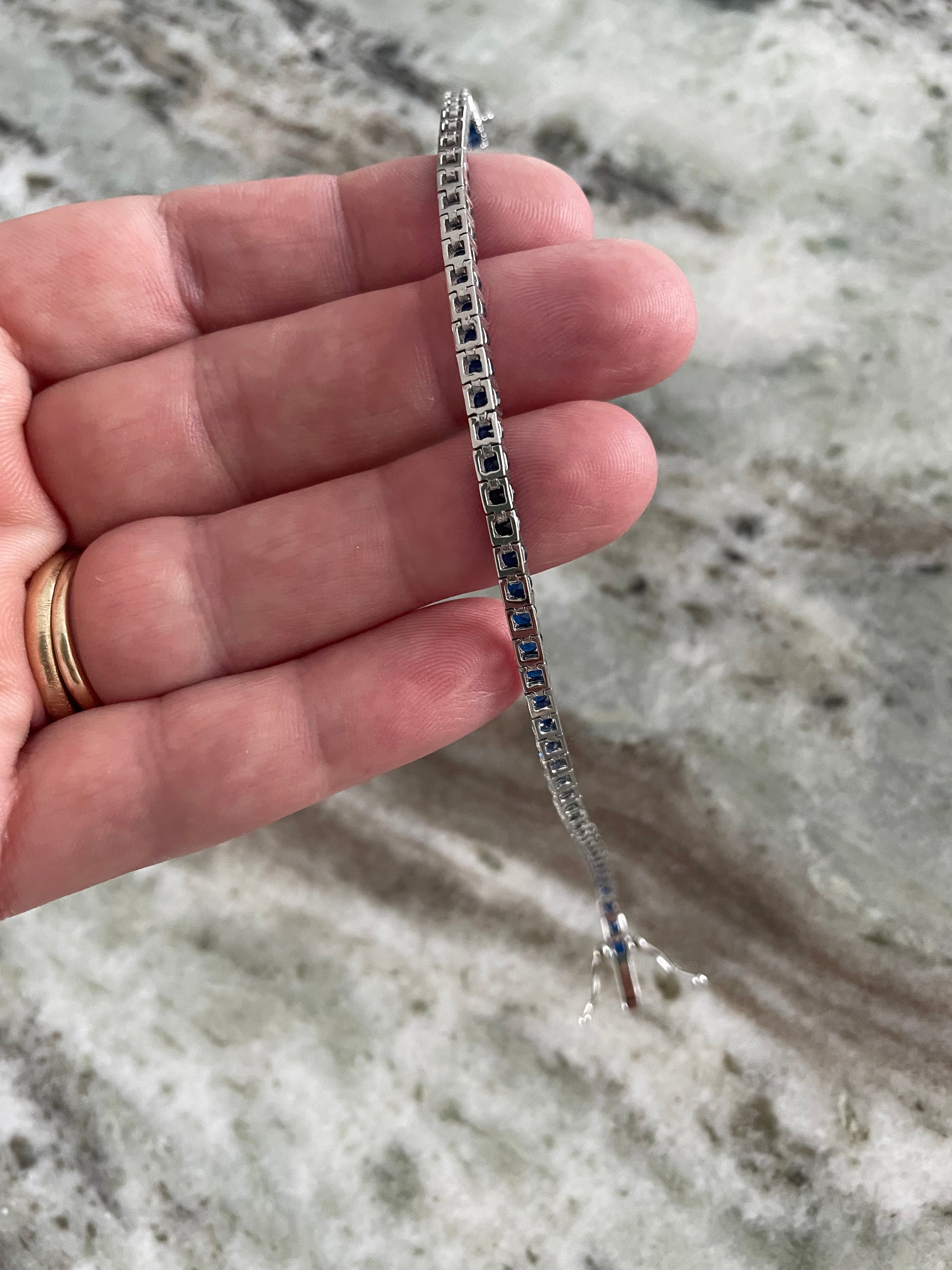 dainty sapphire tennis bracelet with sparkling blue stones in silver prong setting