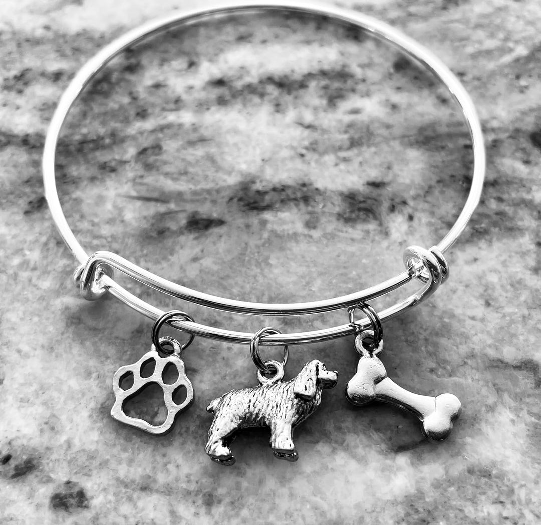 Silver expandable wire bangle bracelet with three charms: cutout paw print charm, Cocker Spaniel dog figurine charm, and double-sided dog bone charm — meaningful gift for dog moms and Cocker Spaniel lovers