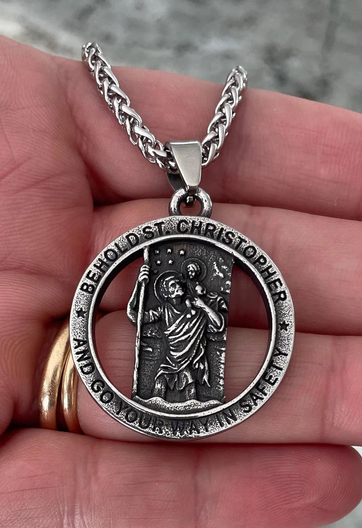 Saint Christopher medal necklace with 31mm pendant on a 24-inch chain, held in hand, symbolizing travel protection