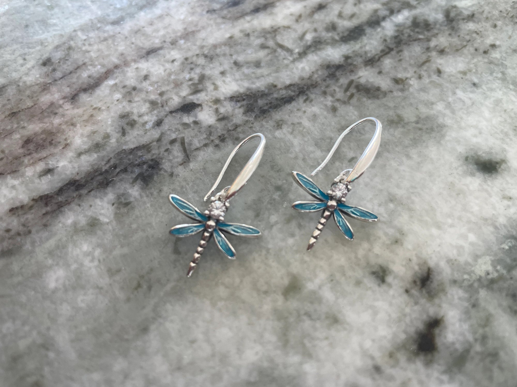 Delicate sterling silver dragonfly earrings with blue enamel wings and CZ crystal center