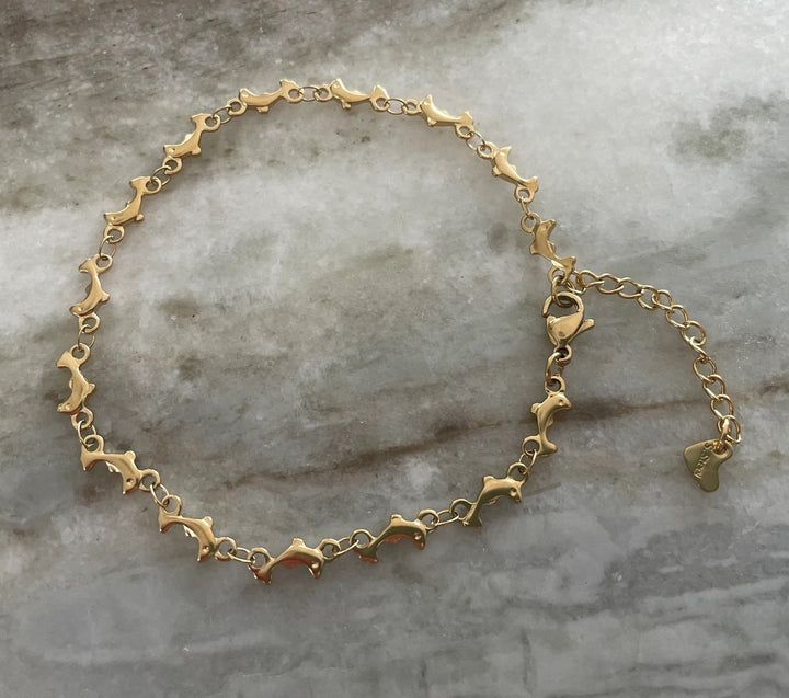A gold-colored stainless steel anklet with a dolphin theme anklet