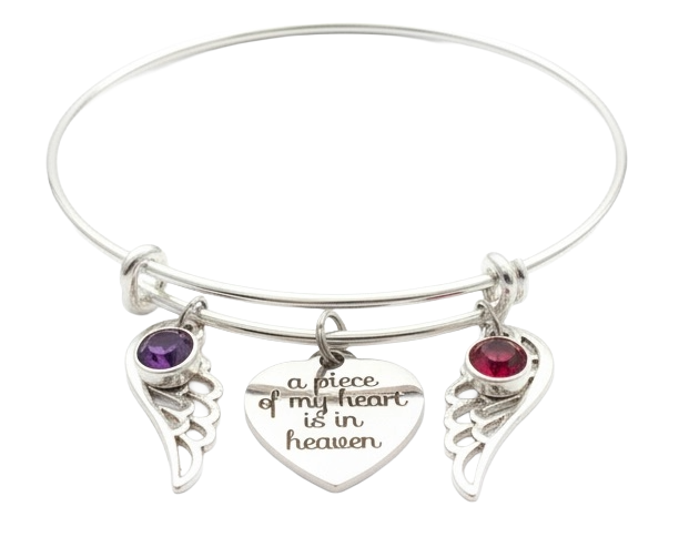 Silver memorial bangle bracelet with two angel wing charms, purple and red birthstone crystals, and engraved "a piece of my heart is in heaven" heart pendant

