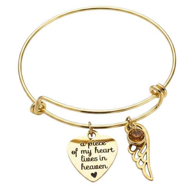 Gold expandable bangle bracelet with engraved "a piece of my heart lives in heaven" heart charm, gold angel wing, and amber birthstone crystal


