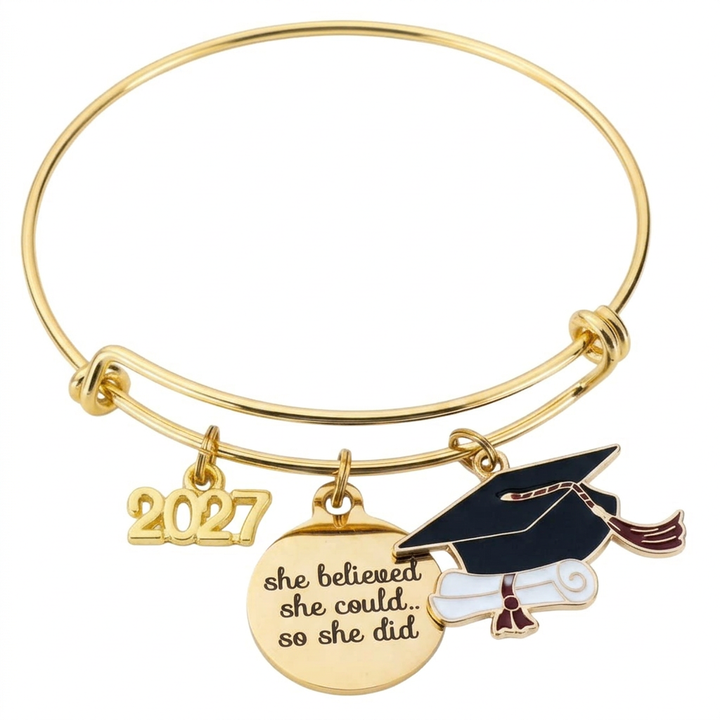 Gold-tone graduation bangle with a 2027 year charm, “she believed she could... so she did” charm, and black graduation cap with diploma.
