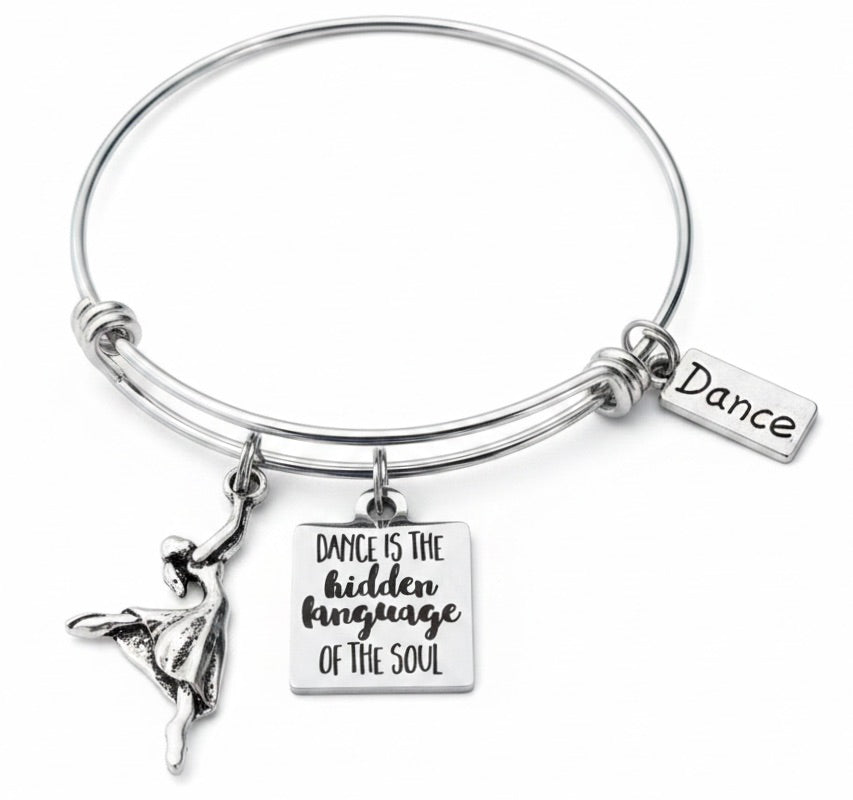 Close-up of silver-plated ballerina dancer charm and engraved dance quote charm on expandable wire bangle bracelet

