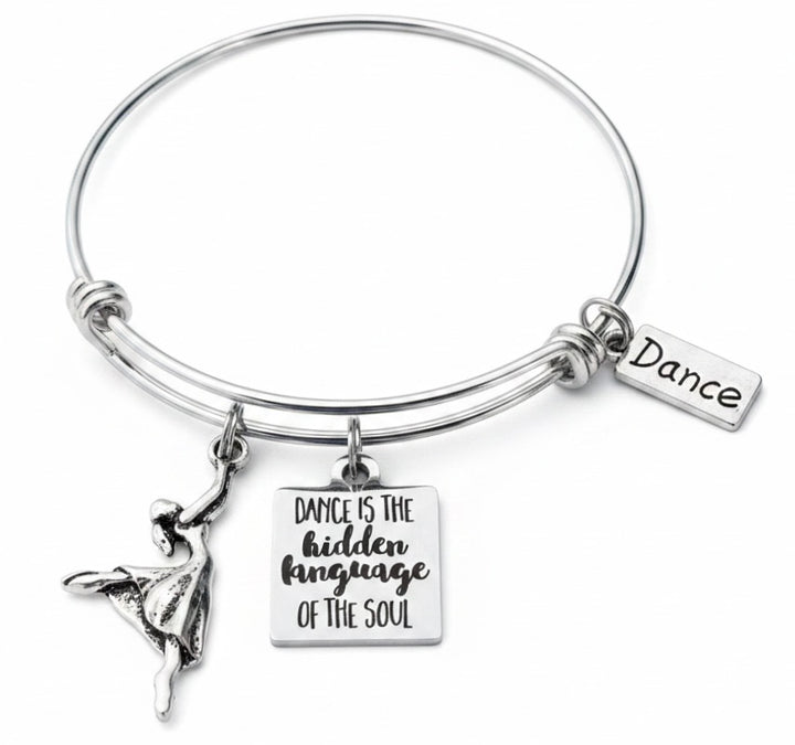 Close-up of silver-plated ballerina dancer charm and engraved dance quote charm on expandable wire bangle bracelet
