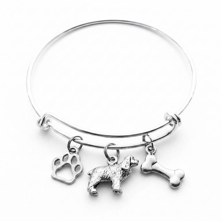 Silver-plated expandable wire bangle bracelet with three charms: cutout paw print charm, detailed 3D Cocker Spaniel dog figurine charm, and double-sided dog bone charm — meaningful gift for dog moms and Cocker Spaniel lovers