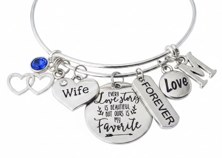 Silver-plated adjustable bangle bracelet featuring an Every Love Story is Beautiful But Ours is My Favorite disc charm, Wife heart charm, double open heart charm, FOREVER bar charm, Love oval charm, sapphire blue birthstone charm, and personalized initial charm — romantic wife gift