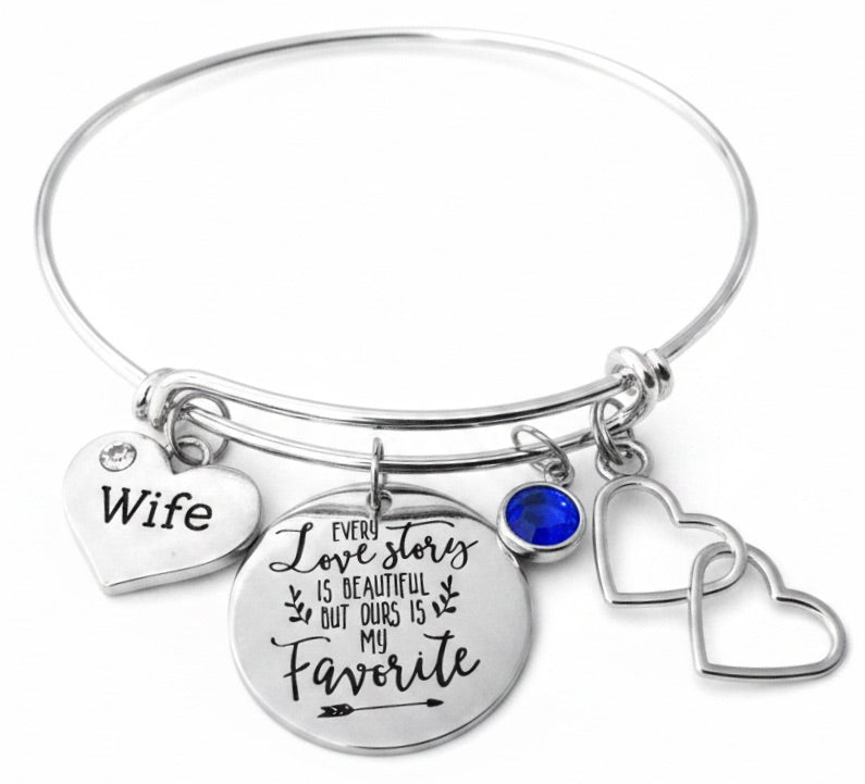 Silver expandable wife charm bracelet featuring Every Love Story is Beautiful But Ours is My Favorite disc charm, Wife heart charm, sparkling round birthstone bead, and double open hearts charm — personalized anniversary gift