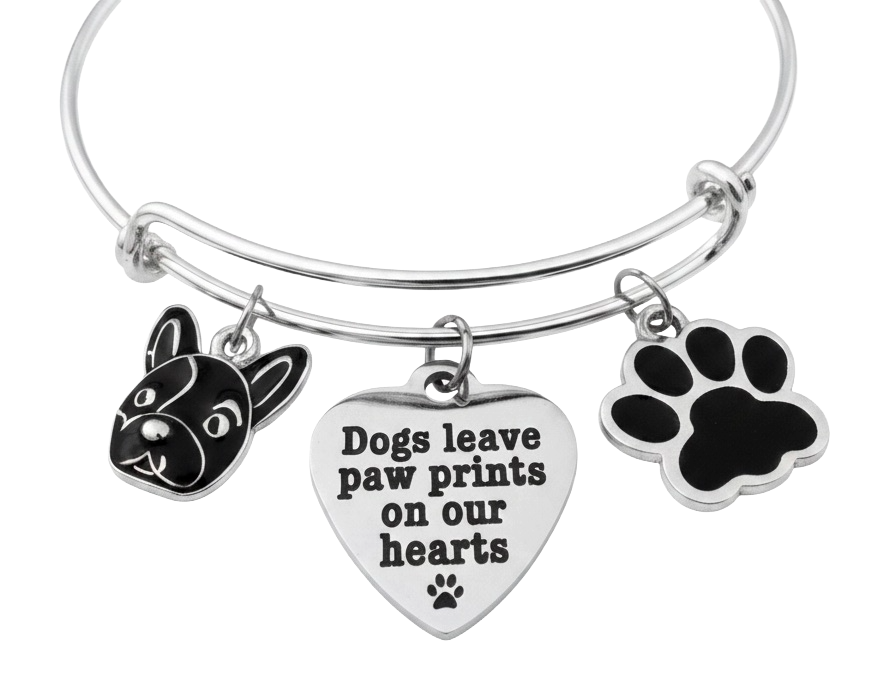 A silver-tone expandable wire bangle bracelet with three charms: a black-and-white French bulldog head, a silver heart charm with the engraved text 'Dogs leave paw prints on our hearts' and a small paw print, and a black paw print charm