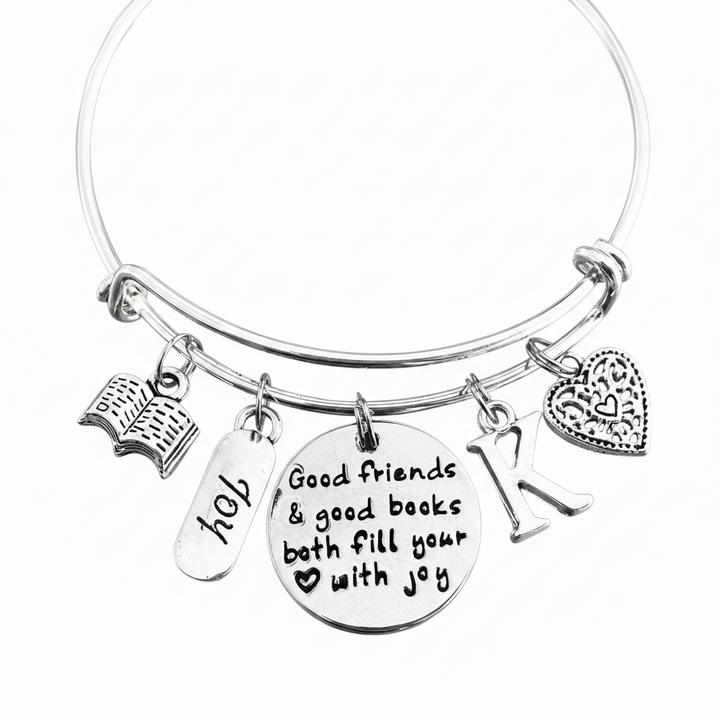 Personalized silver expandable bangle bracelet with open book charm, JOY tag, engraved Good Friends and Good Books quote disc, letter K initial charm, and filigree heart charm — gift for book lovers and best friends