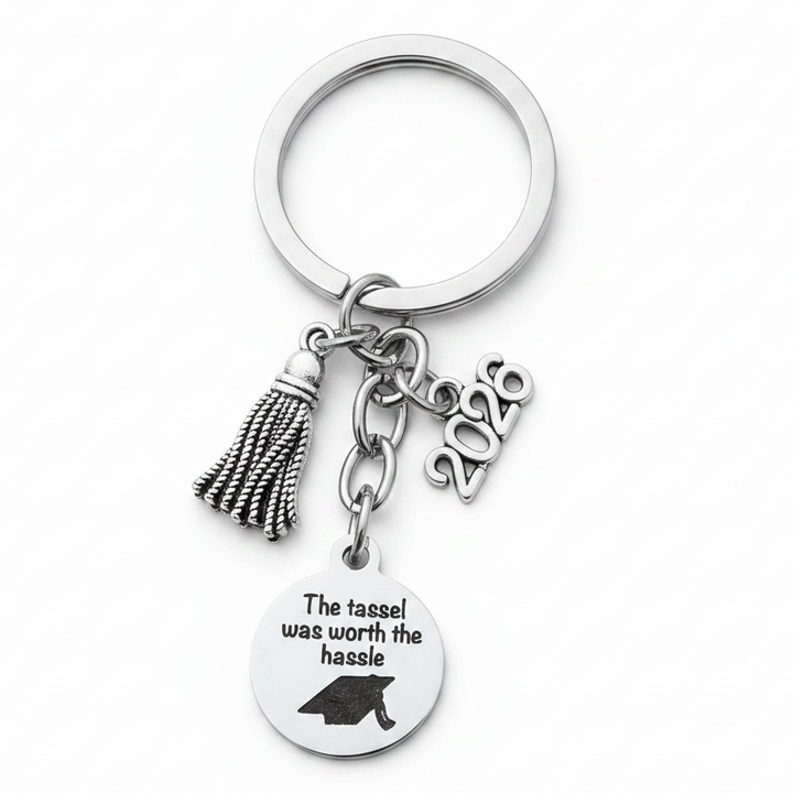 Silver graduation keychain held in hand showing tassel charm, 2026 year charm, and engraved disc reading The tassel was worth the hassle with graduation cap, Class of 2026 gift