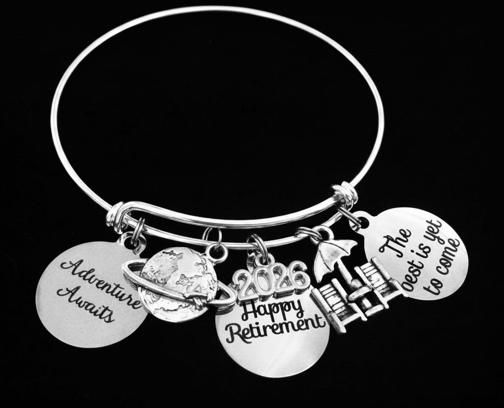 Happy Retirement 2026 silver charm bracelet with globe, beach chair, and engraved sentiment charms on black background – adjustable bangle gift for women by Jules Obsession