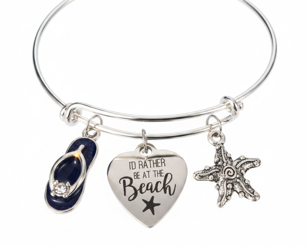 A silver bangle bracelet with three charms: a navy blue flip-flop charm with rhinestones, a silver heart charm engraved with &