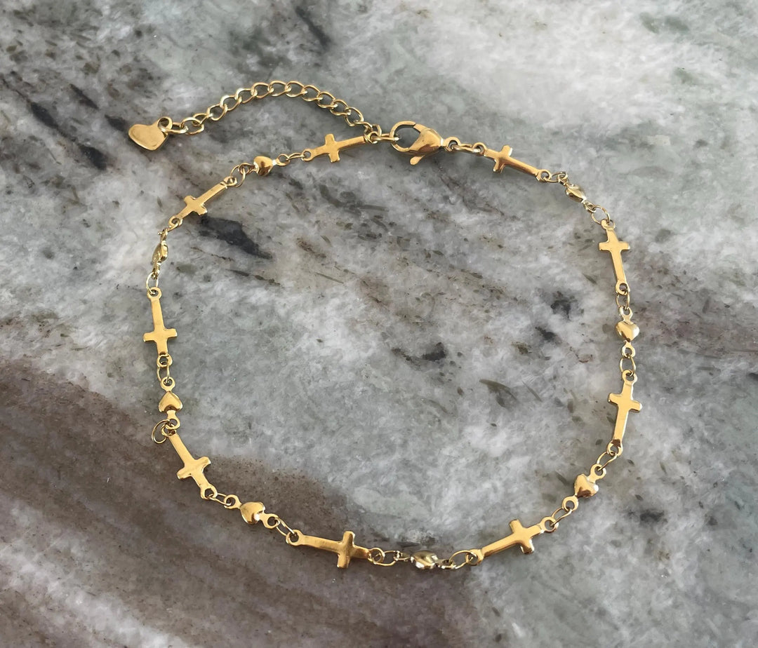 Delicate gold-tone stainless steel anklet featuring alternating flat cross charms and small heart links on a fine chain, with a lobster clasp and heart extender charm — displayed on a white background.
