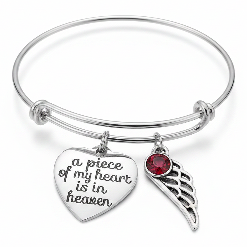 Silver memorial bangle bracelet with two angel wing charms, purple and birthstone crystals, and engraved a piece of my heart is in heaven heart pendant