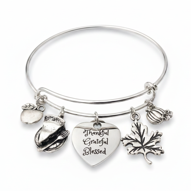 Silver expandable wire bangle bracelet on white background featuring four Thanksgiving charms on individual jump rings: turkey, Thankful Grateful Blessed engraved heart, maple leaf, and ribbed pumpkin