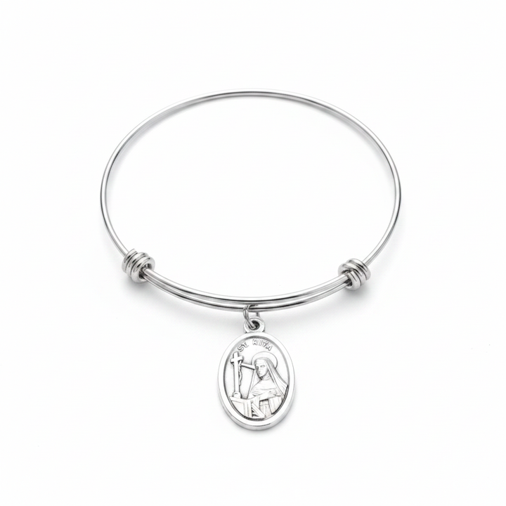Saint Rita patron saint bangle bracelet with silver oxidized oval medal charm on adjustable stainless steel wire bangle, studio photo on white background