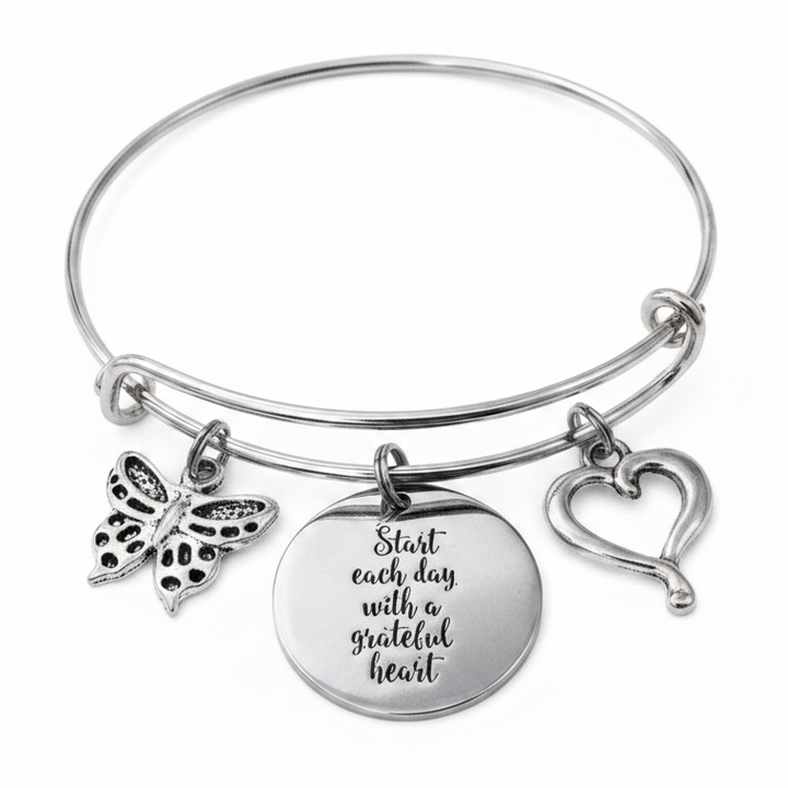 Silver expandable bangle bracelet with Start Each Day With a Grateful Heart engraved disc charm, butterfly charm, and open heart outline charm on white background – Jules Obsession inspirational gift jewelry