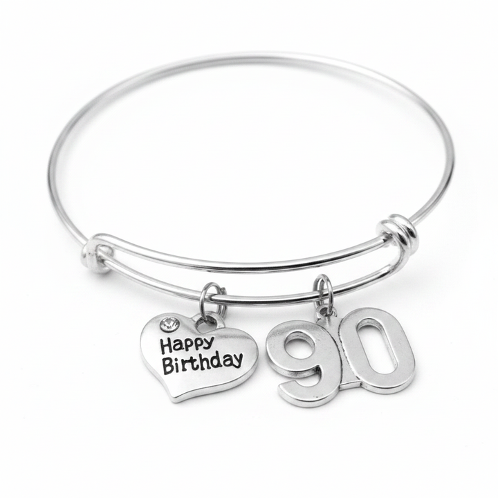 Silver expandable charm bangle bracelet with Happy Birthday heart charm featuring crystal accent and bold 90 number charm, displayed on white background — 90th birthday gift for women by Jules Obsession