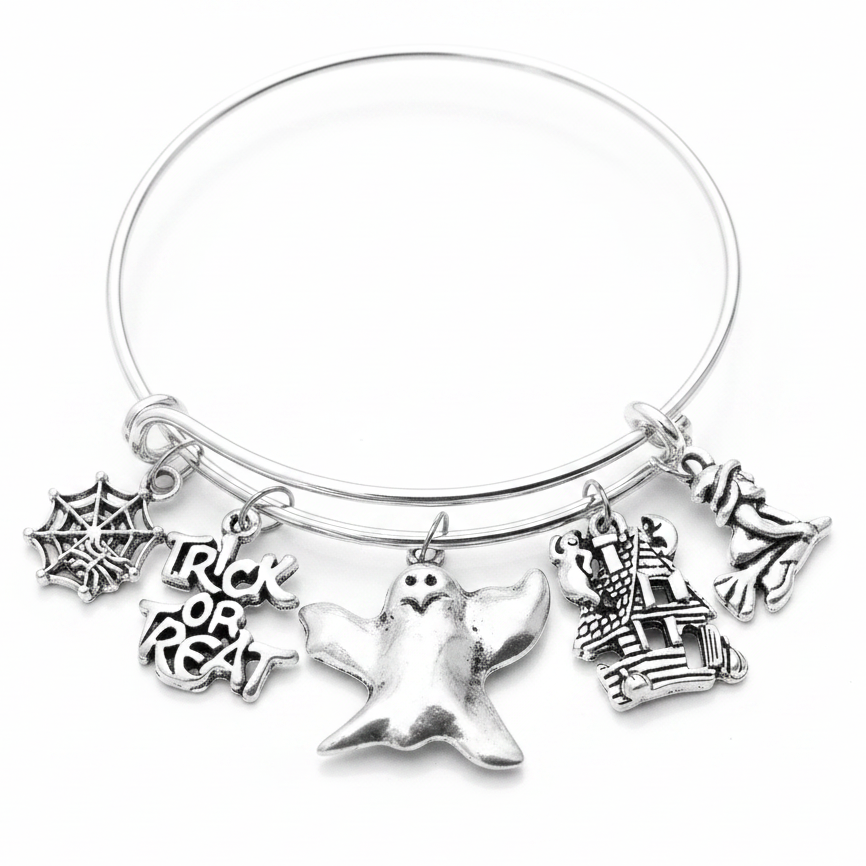Silver adjustable bangle bracelet with five Halloween charms including spider web, Trick or Treat text, ghost, haunted house, and witch on a white studio background