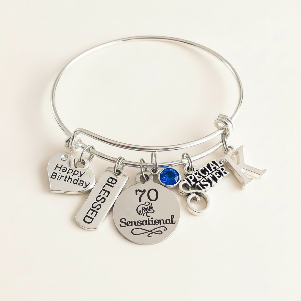 Silver bangle bracelet with engraved Happy Birthday, Blessed, 70 and Special Sister charms, featuring a royal-blue birthstone on a clean white studio background