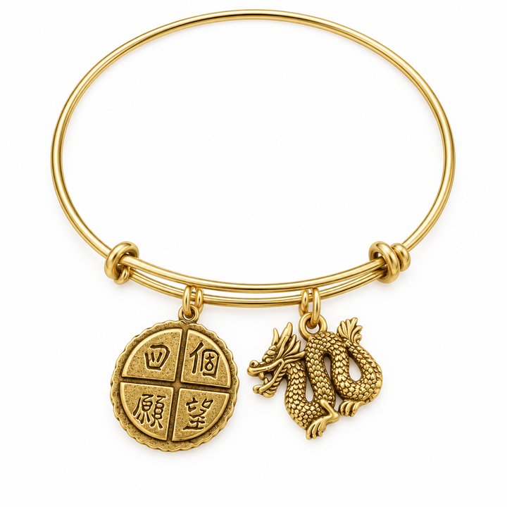 Gold bangle bracelet with a Four Wishes coin charm and a 3D gold dragon charm, shown on a warm-white studio background