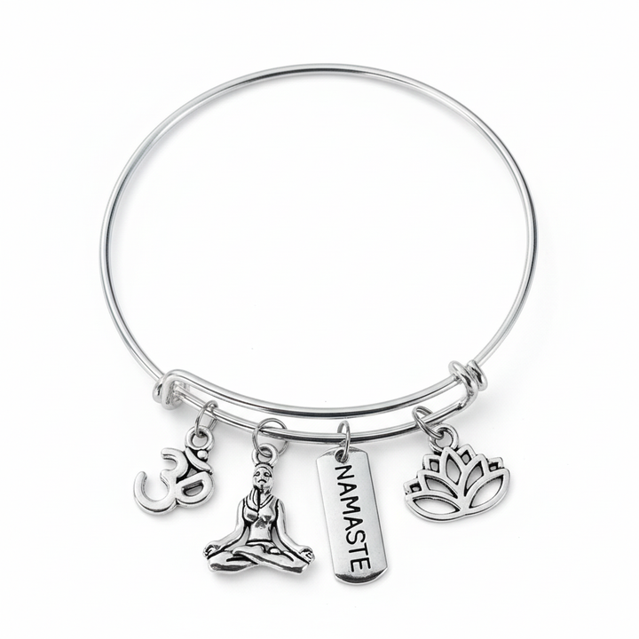 Silver expandable bangle bracelet with an Om symbol, seated meditation figure, NAMASTE tag, and lotus charm on a clean white studio background
