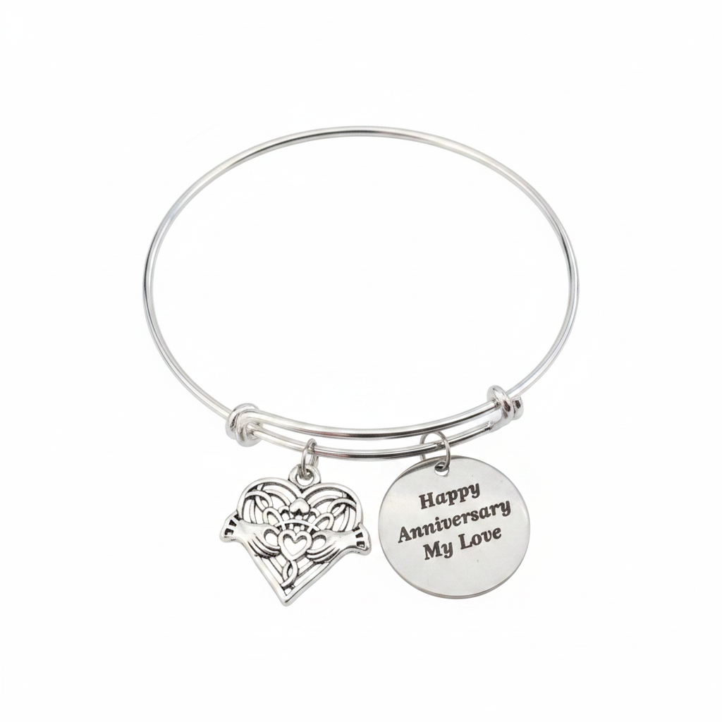 Professional white background studio photo of silver Happy Anniversary My Love bracelet with Claddagh heart filigree charm and engraved round disc charm – romantic anniversary jewelry gift