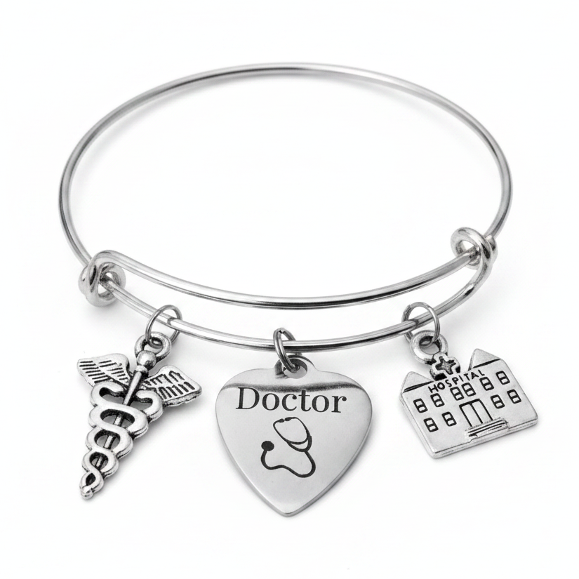 Silver stainless steel bangle charm bracelet featuring a caduceus medical symbol charm, a heart charm engraved with Doctor and stethoscope, and a hospital building charm — gift-ready jewelry for doctors and medical professionals