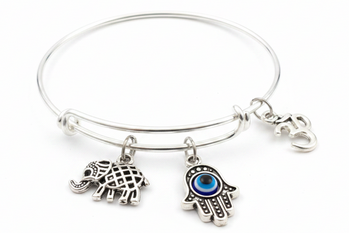 Silver expandable bangle bracelet with Hamsa hand evil eye charm, Om symbol charm, and lucky elephant charm on white background – Jules Obsession spiritual protection jewelry