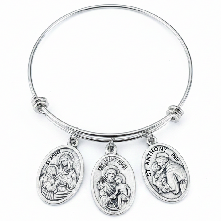 Silver adjustable bangle bracelet with three antique silver oval saint medal charms — St. Anne, St. Joseph, and St. Anthony — displayed on a white studio background